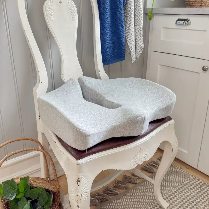 Tryckavlastande ergonomisk sittkudde i grått minnesskum på vit vintage-stol i heminredningsmiljö