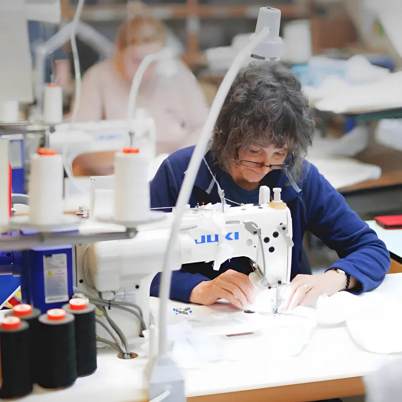 Medarbetare på ErgoSitts lager syr ergonomiska kuddar för hand med industrisymaskin.