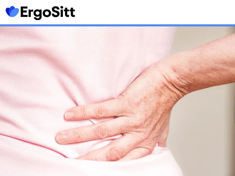 Äldre person med smärta i ländryggen – symboliserar behovet av ergonomisk ryggkudde för stöd och smärtlindring vid stillasittande.