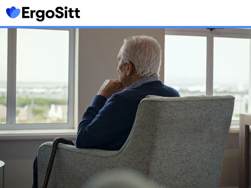 Äldre man sitter i fåtölj med käpp – symbol för behovet av ergonomiskt stöd och trygghet i vardagssittande
