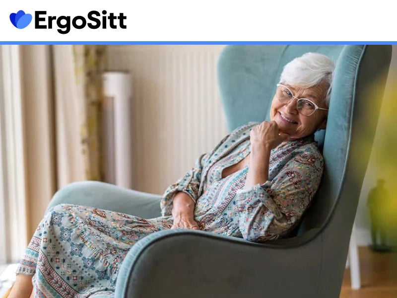 Äldre kvinna sitter bekvämt i fåtölj – symbol för smärtfritt sittande med ergonomiskt ryggstöd och sittkudde
