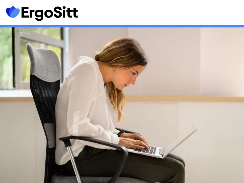 Kvinna med dålig sittställning vid skrivbord som lutar sig framåt – risk för ont i ländryggen vid kontorsjobb