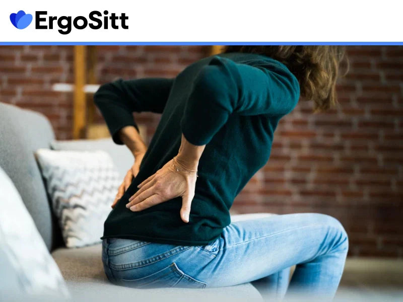 Kvinna med smärta i ländryggen efter att ha suttit stilla i soffan