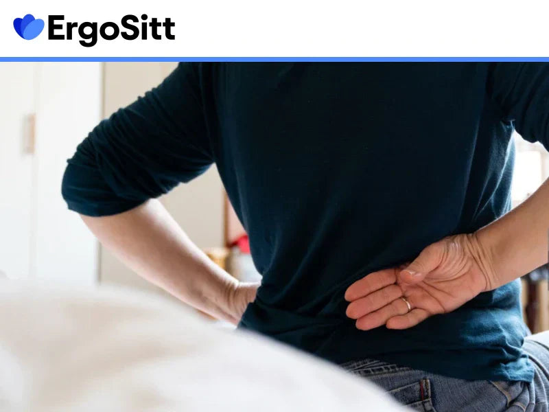 Person med smärta i ländryggen som håller sig för ryggen – illustration av behovet av ländryggsstöd vid kontorsarbete.