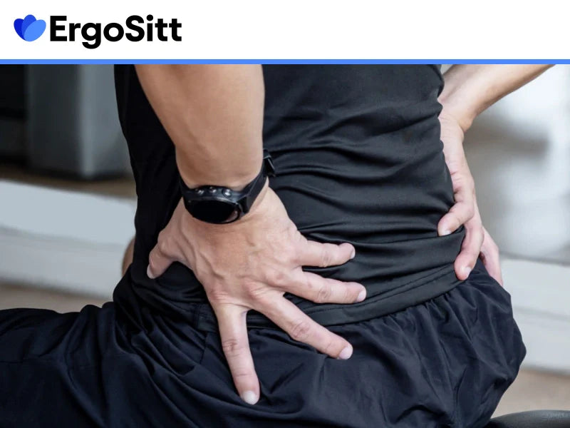 Person med ryggont sitter vid skrivbord och får avlastning med ergonomisk sittkudde och svankstöd för att minska smärta vid stillasittande arbete.