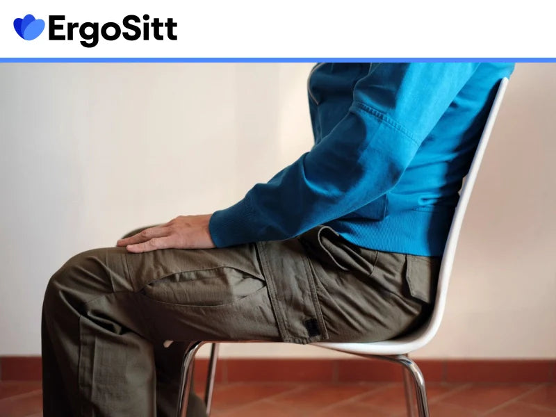 Kvinna sitter ergonomiskt med coccyx-kudde som avlastar svanskotan och minskar smärta vid stillasittande