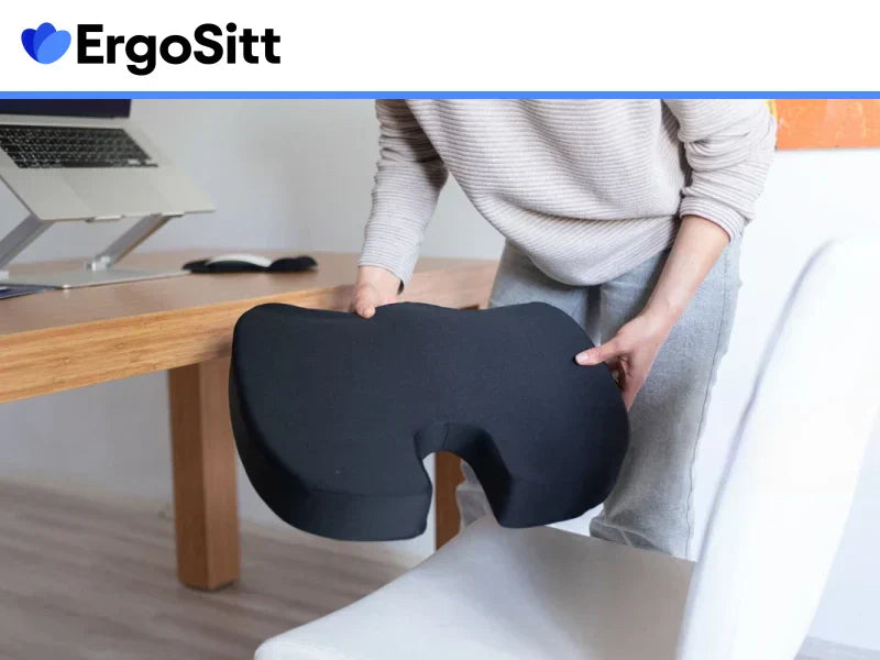 Person placerar ergonomisk sittkudde med urtag för svanskotan på stol framför skrivbord