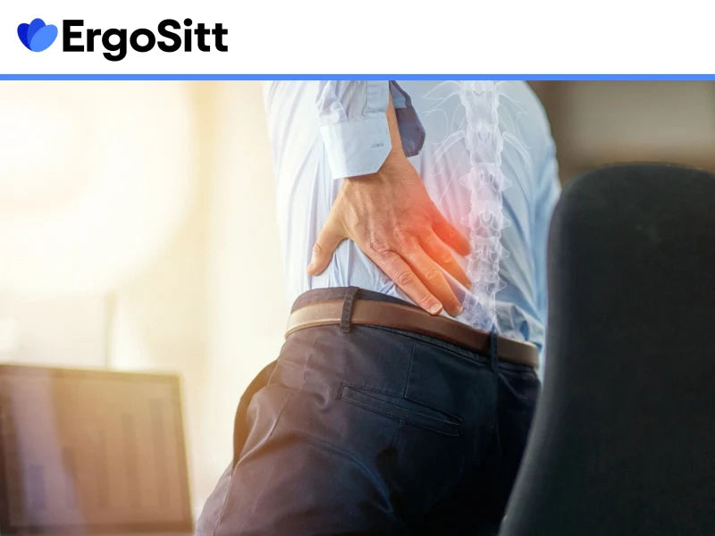 Man med stel rygg på kontoret håller sig för ländryggen efter långvarigt sittande vid skrivbord