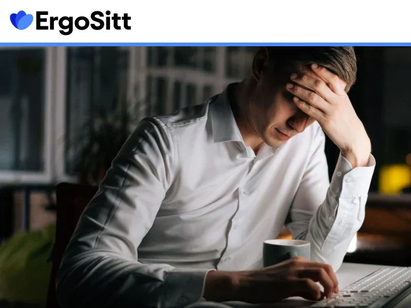 Stressad man framför datorn i dålig arbetsställning – stillasittande kontorsarbete kopplas till mental trötthet och ryggsmärta.