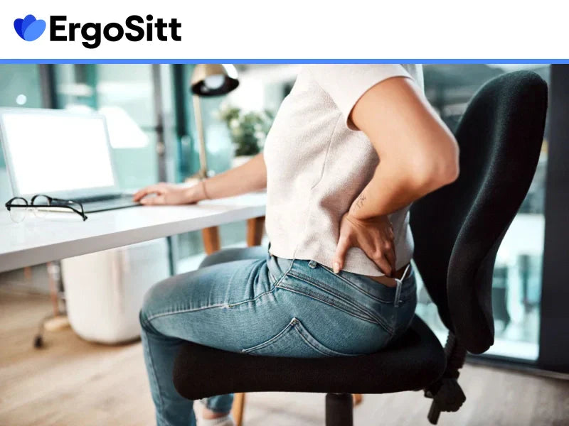 Kvinna med ryggont som sitter på kontorsstol utan ergonomisk sittkudde