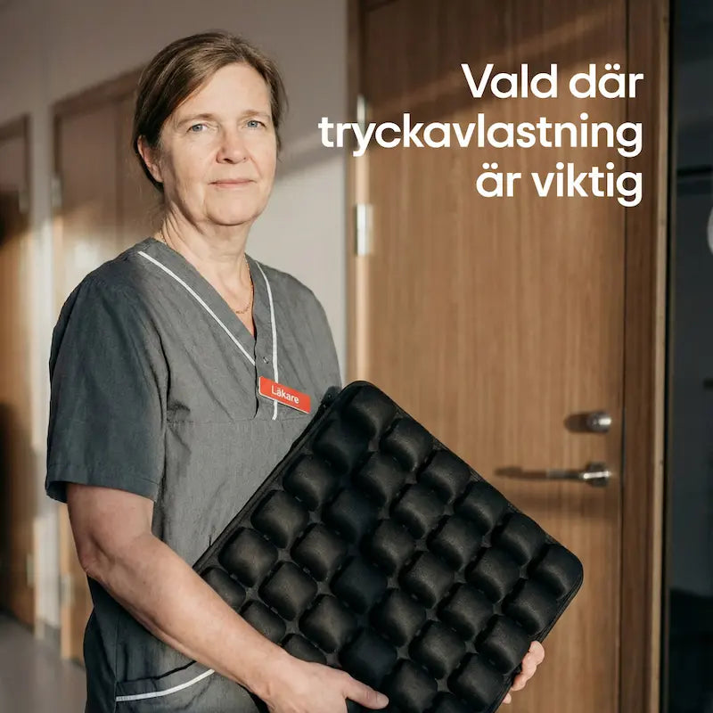 Läkare håller ErgoCell sittkudde i sjukhuskorridor — samma tryckavlastande teknik som används inom vården