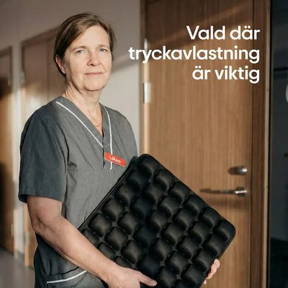 Läkare håller ErgoCell sittkudde i sjukhuskorridor — samma tryckavlastande teknik som används inom vården
