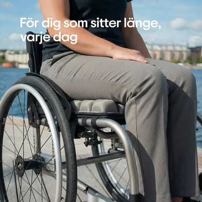 Person sitter på ErgoCell sittkudde i rullstol vid vattnet en solig dag — tryckavlastande sittkudde för dig som sitter länge varje dag