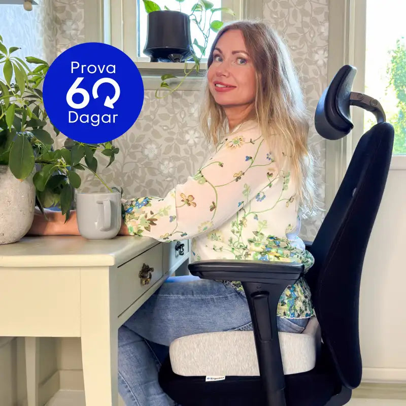 Kvinna sitter bekvämt på ErgoKudden ergonomisk sittkudde på kontorsstol vid hemmakontor — prova riskfritt i 60 dagar