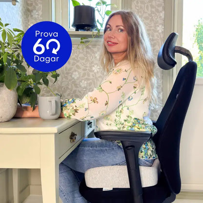 Kvinna sitter bekvämt på ErgoKudden ergonomisk sittkudde på kontorsstol vid hemmakontor — prova riskfritt i 60 dagar