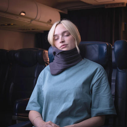 Kvinna sover bekvämt med ErgoNack ergonomisk nackkudde runt halsen i flygplanssäte — stabilt nackstöd under resan