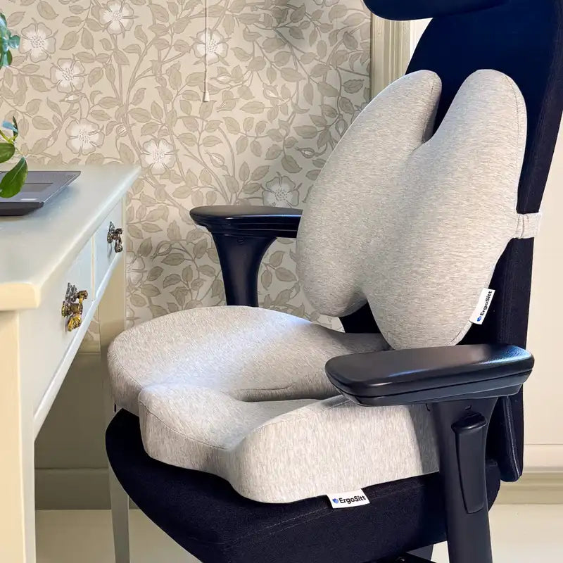 ErgoPaket Pro i grått med ErgoKudden och ErgoStödet monterade på svart kontorsstol vid hemmakontor — komplett ergonomiskt stöd för svanskota och ländrygg