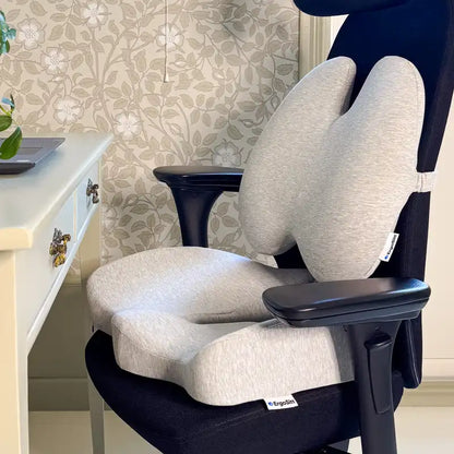 ErgoPaket Pro i grått med ErgoKudden och ErgoStödet monterade på svart kontorsstol vid hemmakontor — komplett ergonomiskt stöd för svanskota och ländrygg