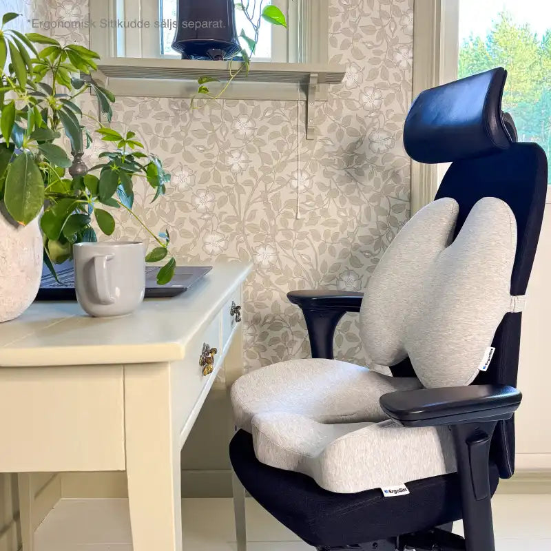 ErgoStödet ländryggskudde och ErgoKudden sittkudde placerade tillsammans på svart kontorsstol vid hemmakontor — komplett ergonomisk sittlösning för rygg och svanskota